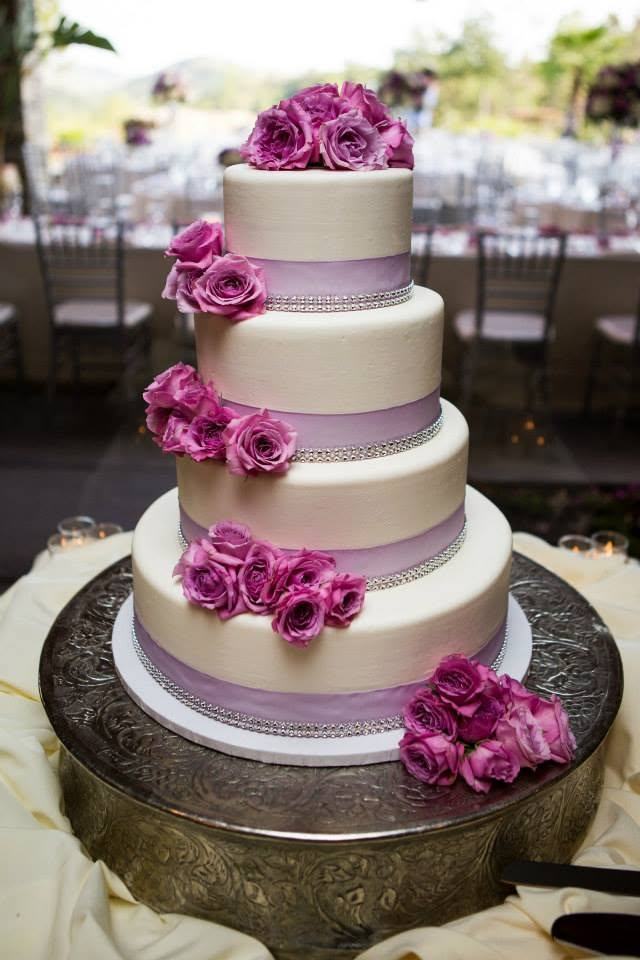 Four-tier wedding cake with lavender ribbon and pink roses