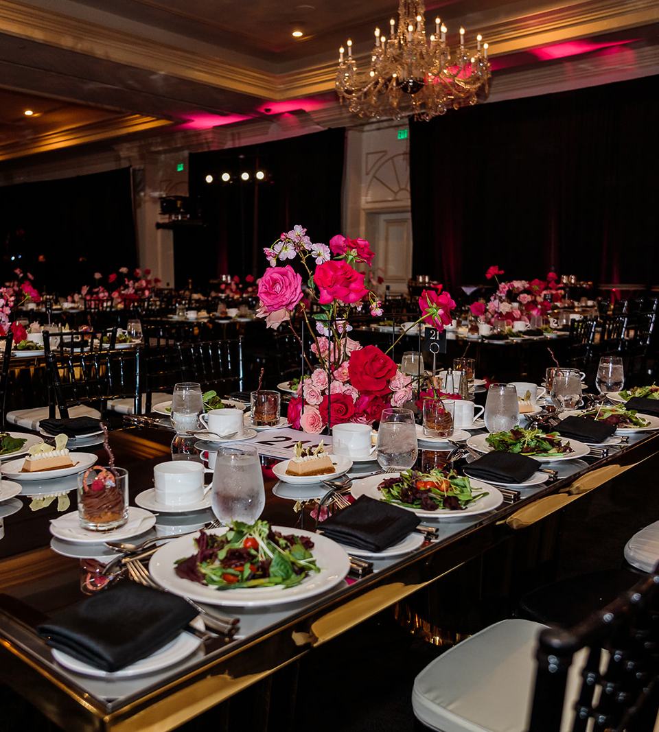 Gala dinner table with pink rose centerpiece under crystal chandeliers