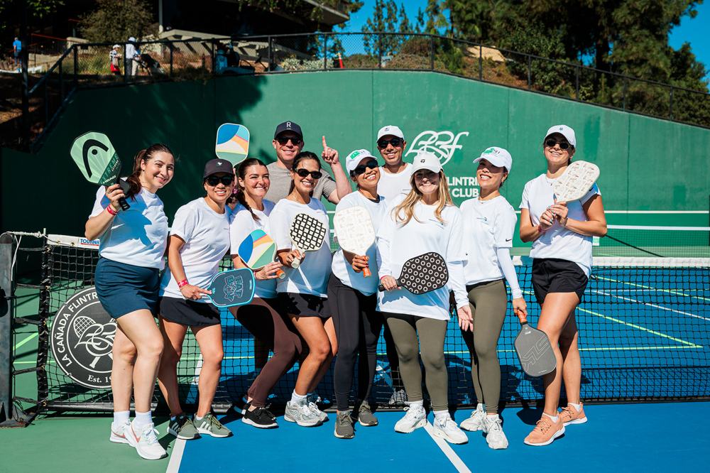 Smiling players holding paddles at a charity pickleball tournament